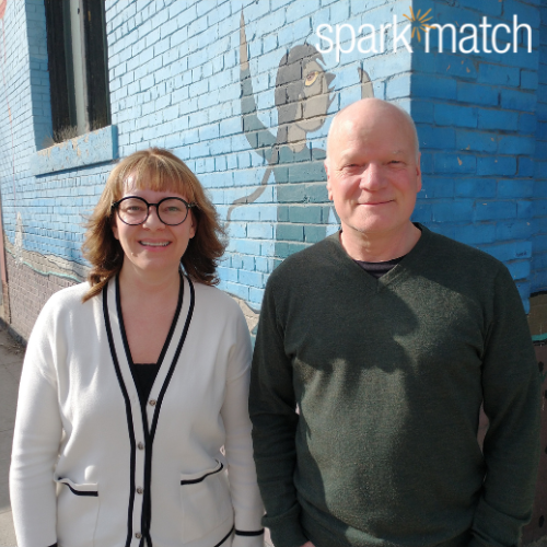 A man and a woman standing in front of a blue brick mural
